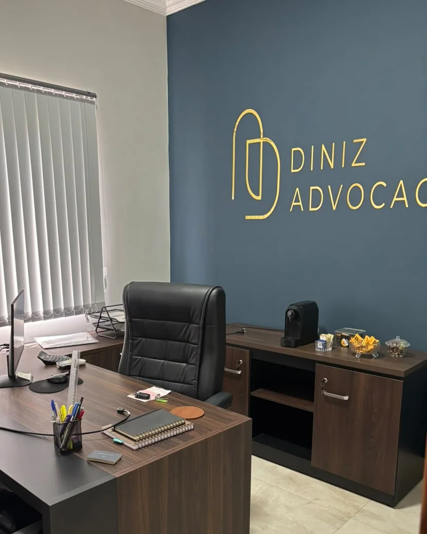 Sala de atendimento da Diniz Advocacia, com mesa de trabalho e o logotipo do escritório na parede